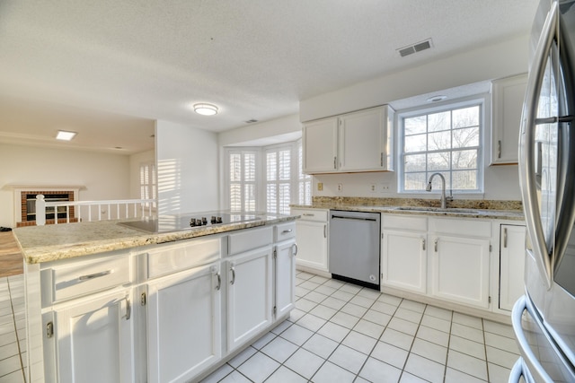 kitchen with stainless steel appliances, a sink, visible vents, white cabinetry, and light stone countertops