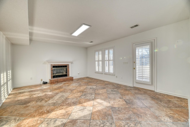 unfurnished living room with stone finish floor, baseboards, a fireplace, and visible vents