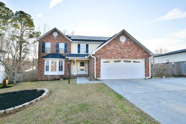 traditional-style home with a garage, brick siding, fence, driveway, and roof mounted solar panels