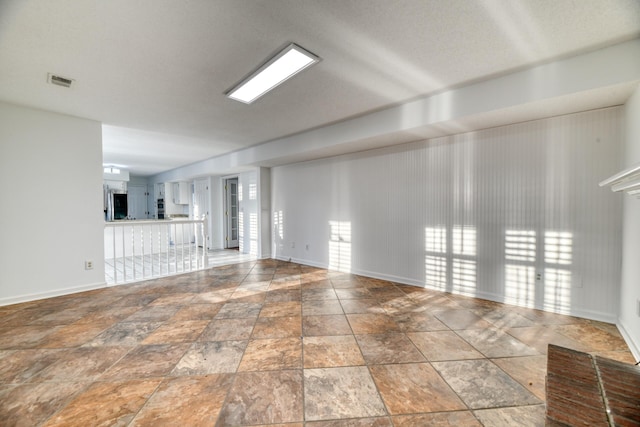 unfurnished living room with stone finish floor, baseboards, and visible vents