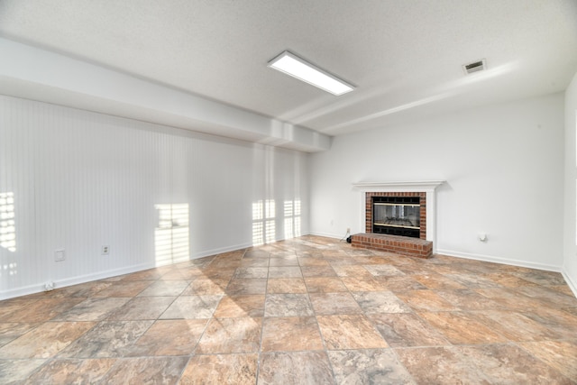 unfurnished living room with stone finish floor, a fireplace, visible vents, and baseboards