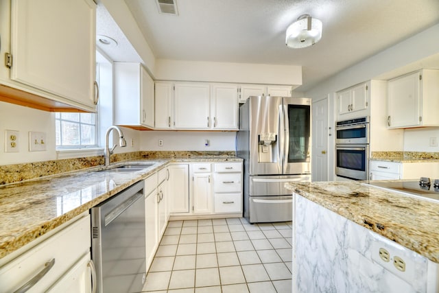 kitchen with light tile patterned flooring, stainless steel appliances, a sink, visible vents, and white cabinetry