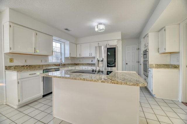 kitchen featuring light tile patterned floors, appliances with stainless steel finishes, a kitchen island, and white cabinets