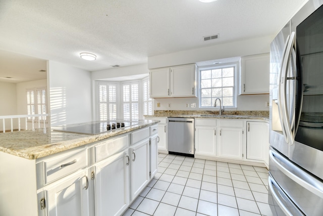 kitchen featuring light tile patterned floors, stainless steel appliances, visible vents, white cabinets, and a sink