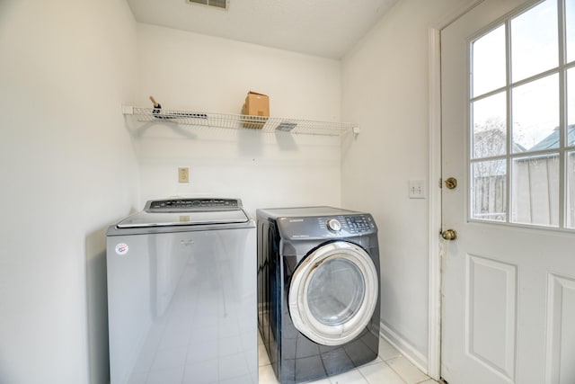 washroom featuring laundry area, visible vents, washer and clothes dryer, and baseboards