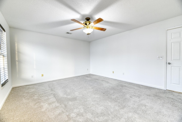 carpeted empty room featuring a ceiling fan, visible vents, a textured ceiling, and baseboards