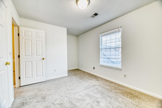 unfurnished bedroom featuring a textured ceiling, carpet flooring, visible vents, and baseboards