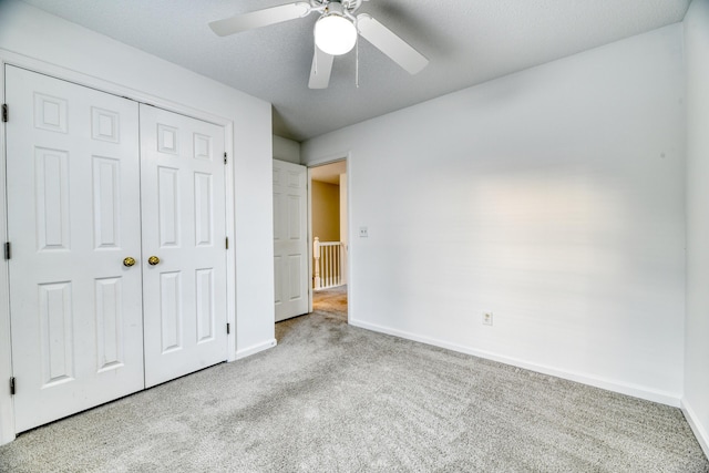 unfurnished bedroom with carpet floors, a ceiling fan, baseboards, and a closet