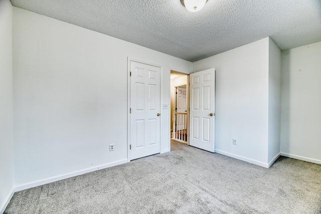 unfurnished bedroom featuring carpet, a textured ceiling, and baseboards