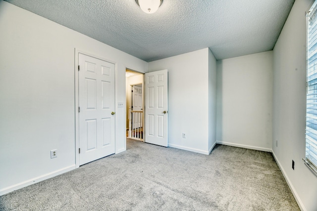 unfurnished bedroom with carpet, a textured ceiling, and baseboards