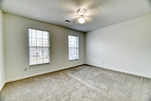 unfurnished room with carpet, visible vents, a textured ceiling, and baseboards