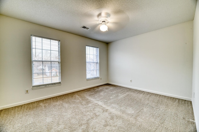 carpeted spare room with baseboards, a textured ceiling, visible vents, and a ceiling fan