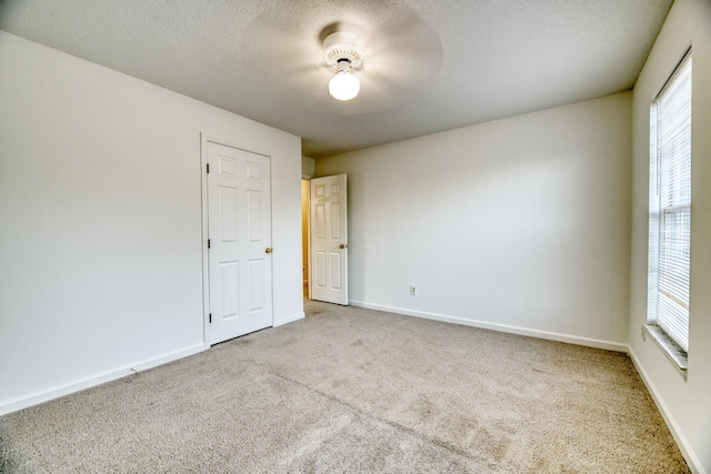 carpeted empty room featuring baseboards and a textured ceiling