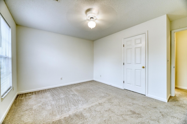 carpeted empty room featuring plenty of natural light, baseboards, and a textured ceiling