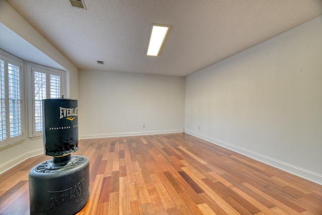 unfurnished room with light wood-type flooring, visible vents, and baseboards