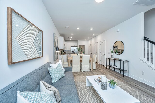 living area with light wood-type flooring, baseboards, visible vents, and recessed lighting