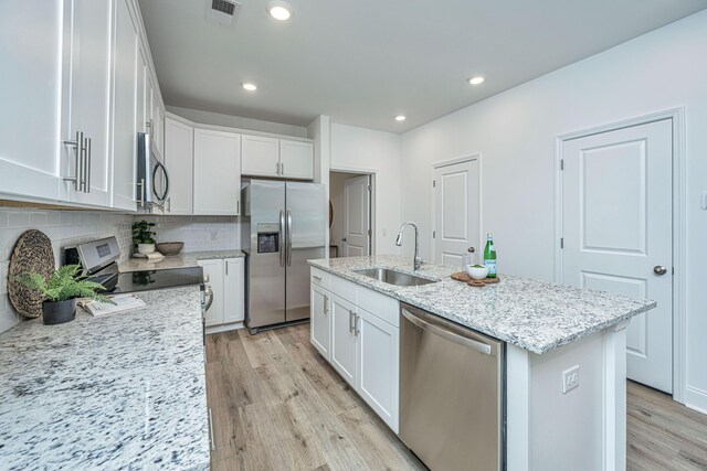 kitchen with appliances with stainless steel finishes, light wood-type flooring, white cabinetry, and a sink