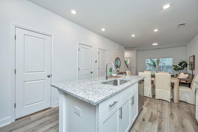 kitchen with visible vents, light wood-style flooring, stainless steel dishwasher, a sink, and an island with sink