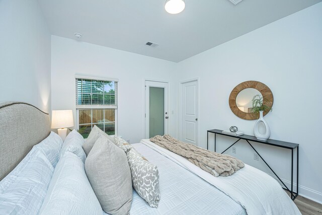 bedroom with visible vents, baseboards, and wood finished floors