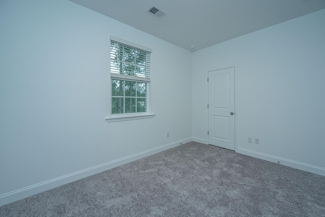 carpeted spare room featuring baseboards and visible vents