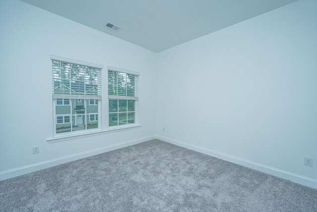 carpeted spare room featuring baseboards and visible vents