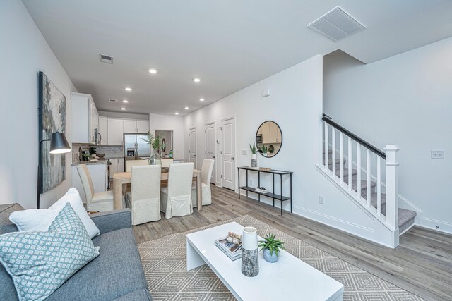 living area with stairway, visible vents, light wood-style floors, and recessed lighting