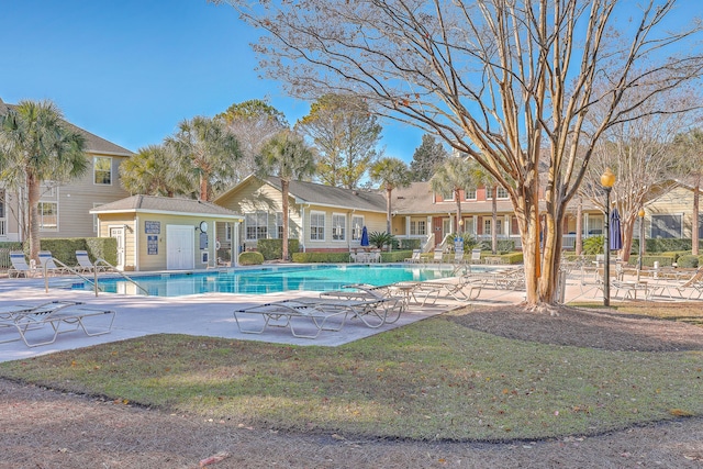 view of swimming pool with a patio, an outdoor structure, and a lawn