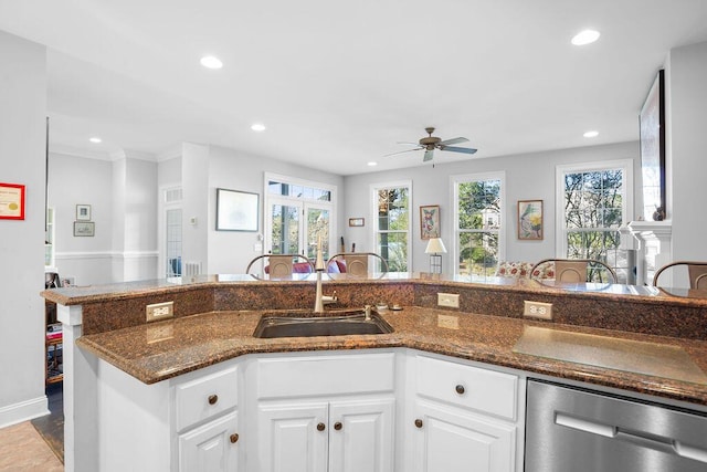 kitchen with ceiling fan, sink, dishwasher, dark stone countertops, and white cabinets