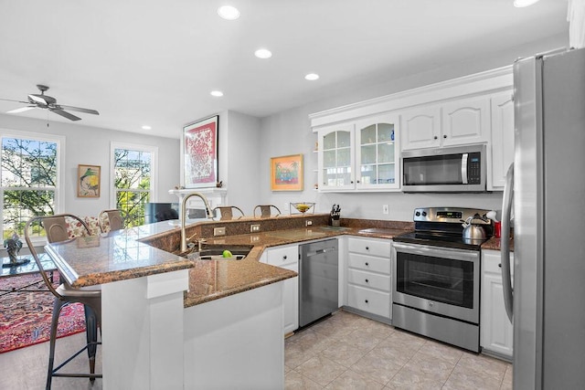 kitchen with sink, kitchen peninsula, a breakfast bar area, white cabinetry, and stainless steel appliances