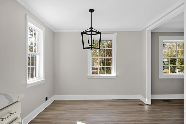 unfurnished dining area featuring a wealth of natural light, a chandelier, ornamental molding, and wood-type flooring