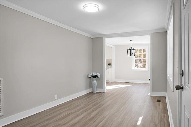 empty room featuring a chandelier, wood-type flooring, and ornamental molding