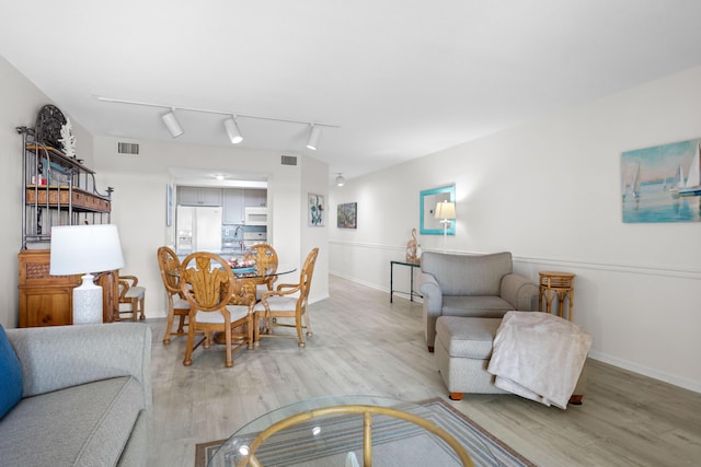 living room featuring baseboards, visible vents, and light wood finished floors