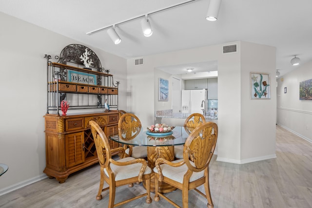 dining area with visible vents, rail lighting, baseboards, and light wood-style floors