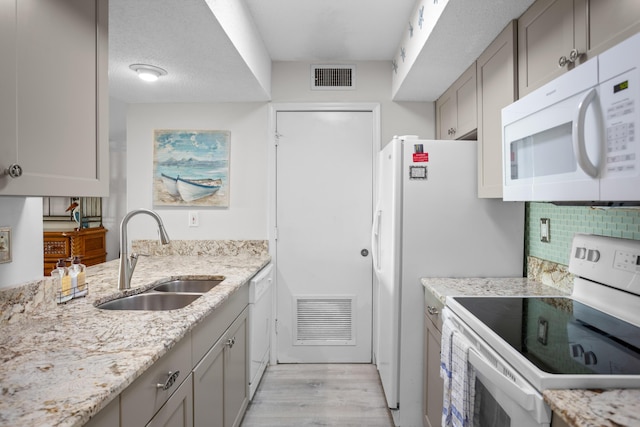 kitchen with a sink, visible vents, white appliances, and gray cabinets