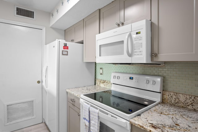 kitchen with white appliances, light stone countertops, visible vents, and backsplash