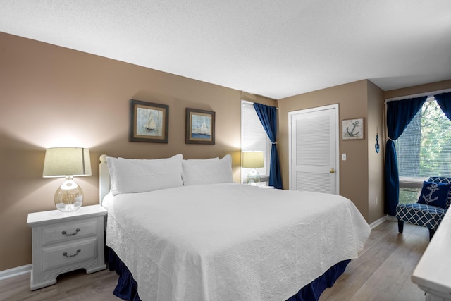 bedroom with a closet, baseboards, and light wood-style floors