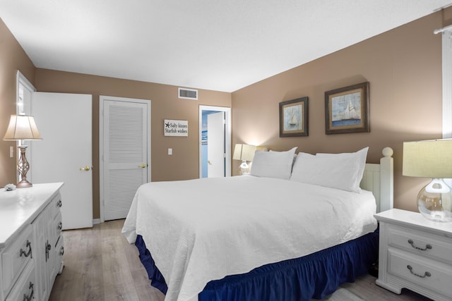 bedroom with a closet, visible vents, and light wood-type flooring