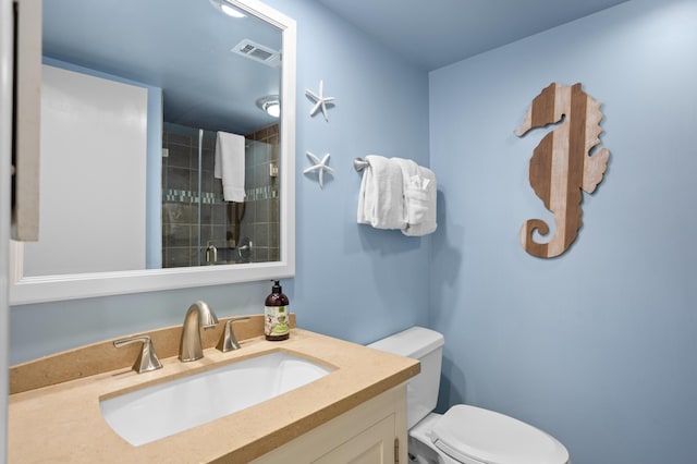 bathroom with a tile shower, visible vents, toilet, and vanity