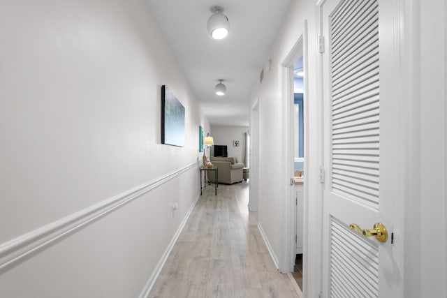 corridor featuring light wood finished floors and baseboards