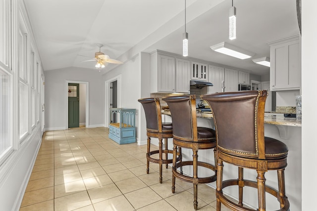 206 Chaussee Blvd, Summerville, SC 29483 - kitchen with baseboards, light tile patterned floors, a kitchen bar, a ceiling fan, and light stone countertops