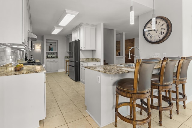 206 Chaussee Blvd, Summerville, SC 29483 - kitchen featuring freestanding refrigerator, a sink, under cabinet range hood, light tile patterned flooring, and white cabinetry