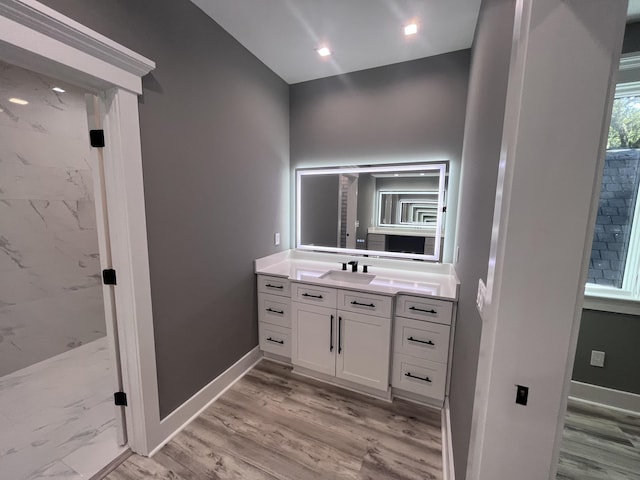 bathroom with hardwood / wood-style flooring, vanity, and walk in shower