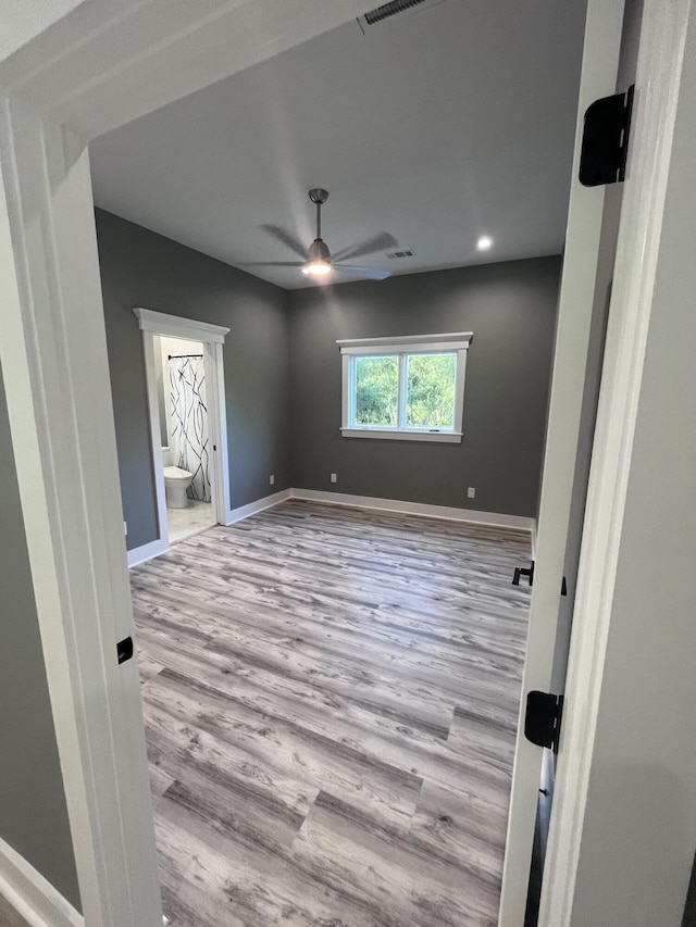 empty room with ceiling fan and light wood-type flooring