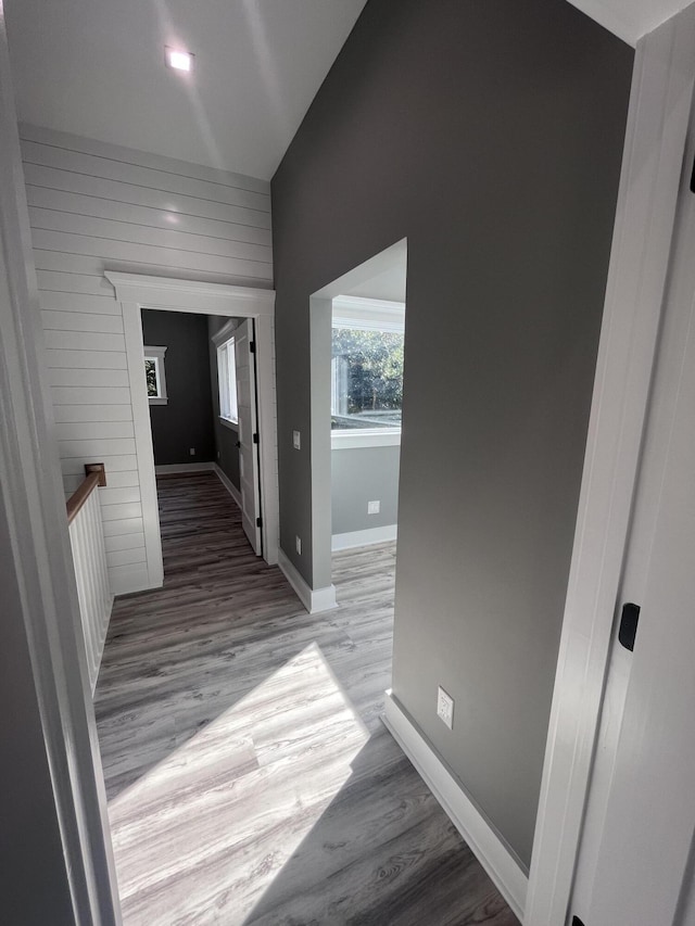 hall with lofted ceiling and light hardwood / wood-style flooring