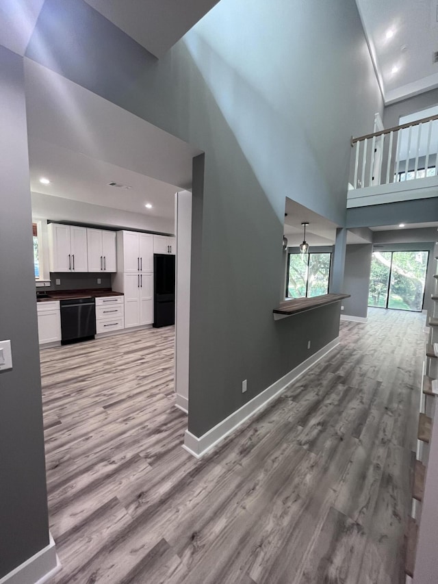 unfurnished living room featuring a towering ceiling and light wood-type flooring