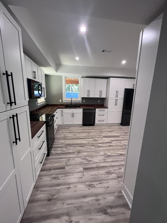 kitchen with white cabinetry, sink, black appliances, and light hardwood / wood-style floors