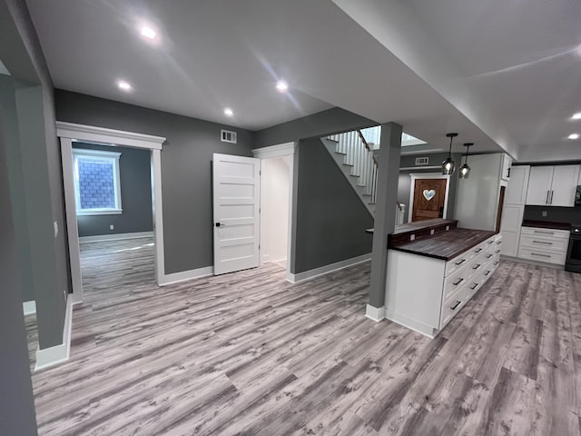 kitchen with decorative light fixtures, electric range, light hardwood / wood-style floors, and white cabinets