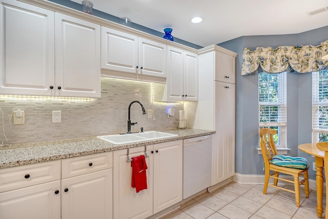 kitchen with white dishwasher, backsplash, light tile patterned floors, and sink