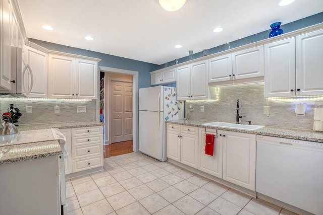 kitchen featuring white appliances, white cabinets, light tile patterned floors, and sink