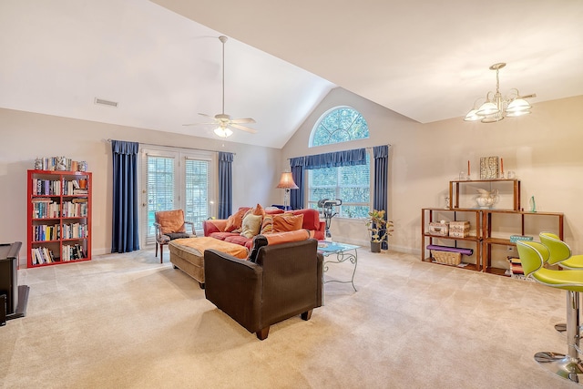 carpeted living room featuring lofted ceiling, a wealth of natural light, and ceiling fan with notable chandelier